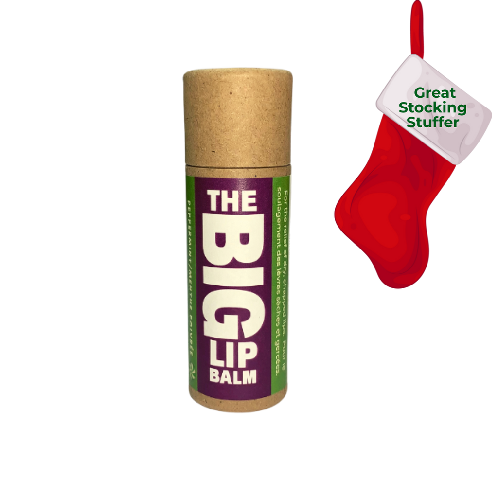 Front view of The BIG Lip Balm in a kraft paper tube with a purple and green label, shown alongside a festive red stocking graphic that reads “Great Stocking Stuffer.